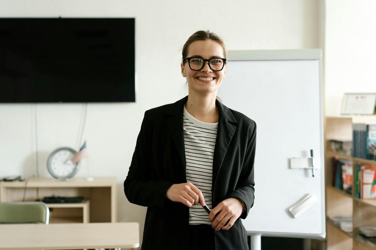 Teacher standing in a classroom beside a whiteboard